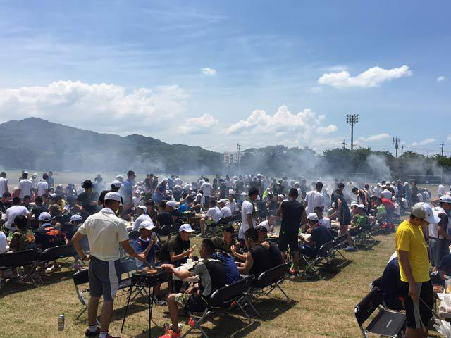 青空の下で仲間と一緒にバーベキューを楽しむ