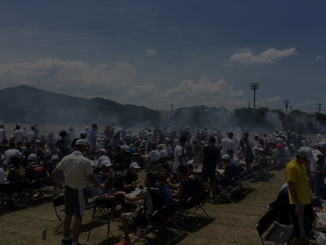 青空の下で仲間と一緒にバーベキューを楽しむ